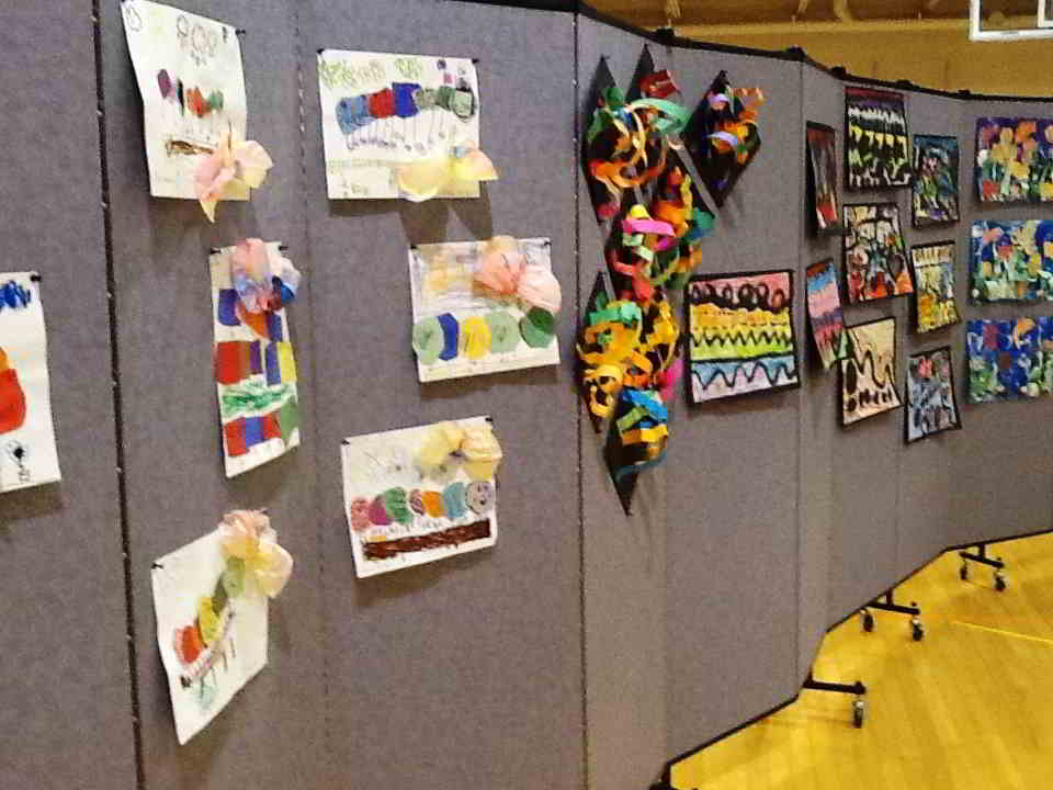 A closeup of student artwork pinned to a Screenflex Room Divider in Lake fabric color