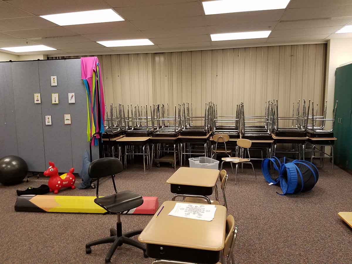 Stacked tables and chairs in a classroom to be hidden behind a movable wall