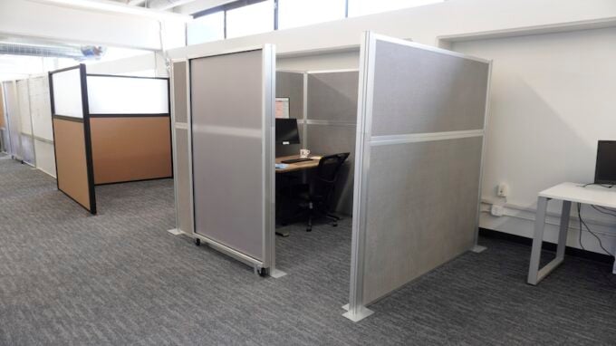 Office cubicles with frosted panels and a desk setup in a modern workspace.