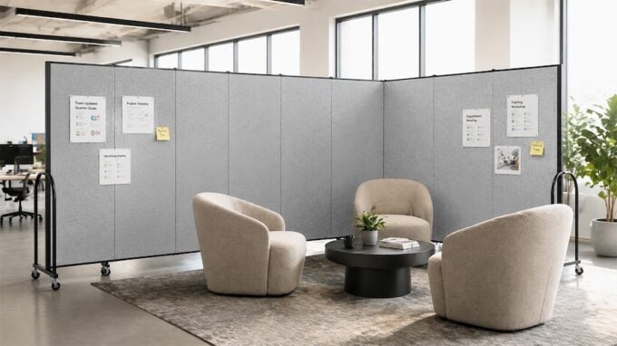 Modern office lounge with gray portable room dividers creating a private collaboration space with chairs and a coffee table.