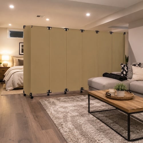 Open living space divided by a folding beige room divider, creating a private bedroom area beside a modern seating and coffee table arrangement.
