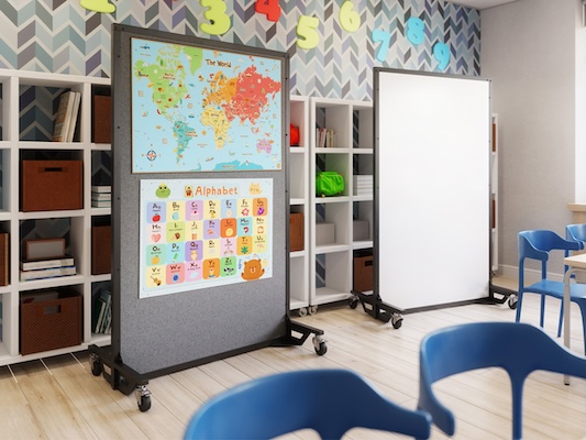 Elementary classroom with two freestanding mobile whiteboards on wheels, one displaying a world map and alphabet learning chart, surrounded by cubby shelves, colorful decorations, and blue student chairs.